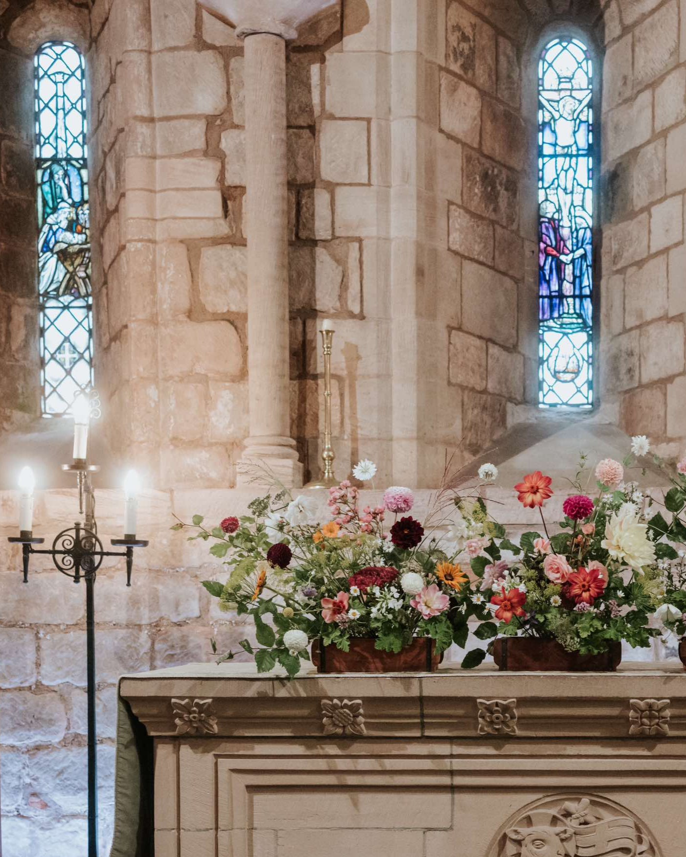a wild array of colourful british grown sustainable wedding flowers sit atop a church alter